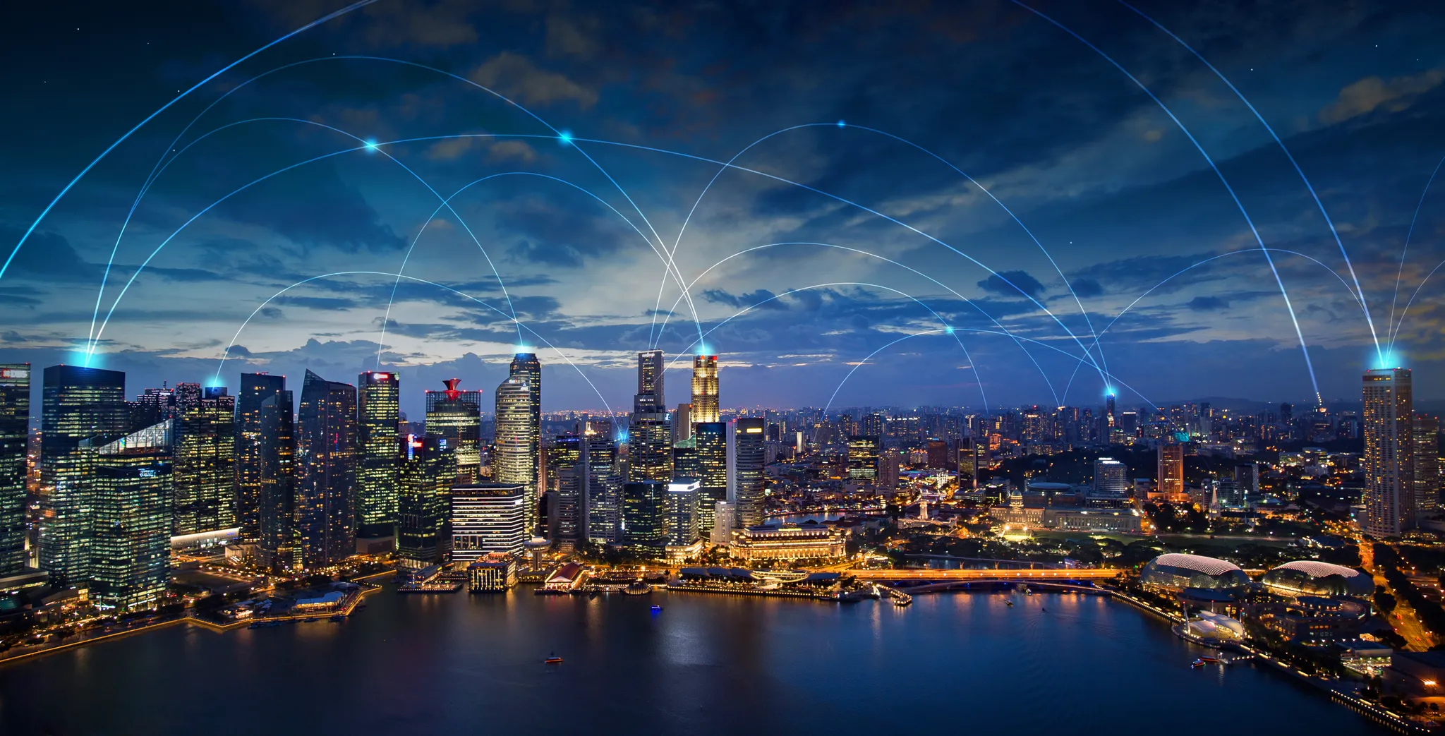 Aerial view of highways crisscrossing a city at night with light beams connecting from spot to spot like a technology network.